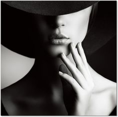 a black and white photo of a woman wearing a hat with her hands on her face