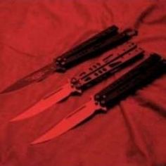 three knives laying next to each other on a red sheet with the knife blades still attached