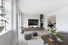 a living room filled with furniture and a flat screen tv mounted on the wall above it