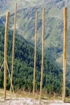 there are many poles in the middle of this mountain side area with mountains in the background