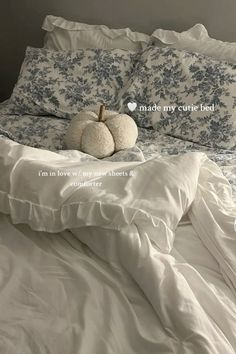 two white pumpkins sitting on top of a bed with ruffled sheets and pillows