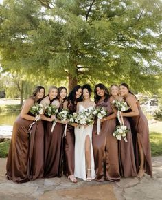 a group of women standing next to each other in front of a tree with flowers