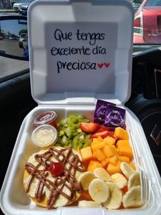 a lunch box filled with fruit and waffles on top of a car dash board