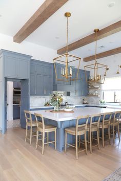 a large kitchen with blue cabinets and wooden flooring, an island table surrounded by chairs