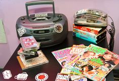 there are many magazines on the table next to a cd player and radio cassette recorder