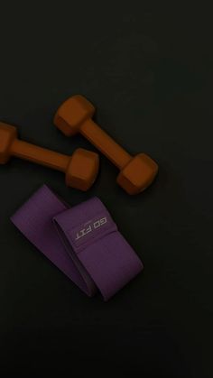 two orange dumbs and one purple towel on a black surface