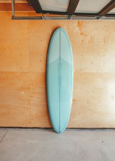 a blue surfboard leaning up against a wooden wall in a room with wood paneling