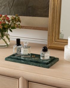 two perfume bottles sitting on top of a wooden tray