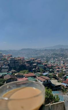 a cup of coffee sitting on top of a table next to a cityscape