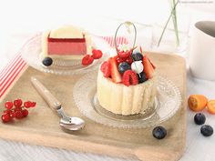 two small cakes with berries and blueberries on a tray