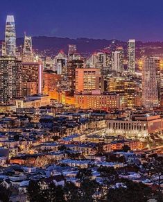 the city is lit up at night with lights on and buildings in the foreground