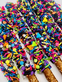 colorful sprinkles and candy sticks are arranged on a white surface to form an abstract pattern