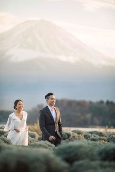 a man and woman standing next to each other in front of a snow covered mountain