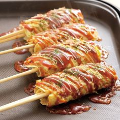 several skewers filled with food sitting on top of a baking pan covered in sauce