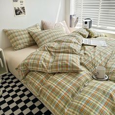 a bed with plaid comforter and pillows on it next to a black and white checkered floor