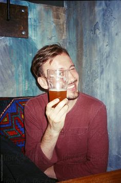 a man sitting at a table with a glass in front of his face and smiling