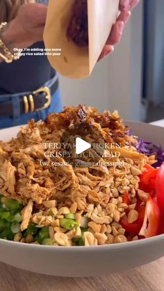 a woman is pouring dressing over a large bowl of rice with vegetables and meat on the side