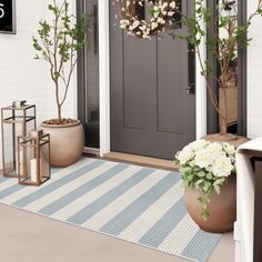 a front door with two planters and flowers on the mat