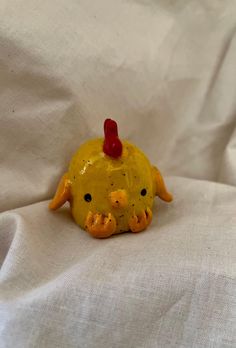 a small yellow toy with a red nose on a white cloth covered bedding area