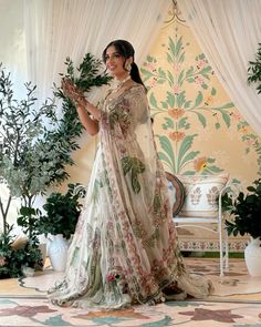 a woman standing in front of a wall with flowers and greenery on the walls