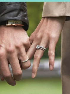 two people are holding hands with rings on their fingers and one is wearing a leather jacket