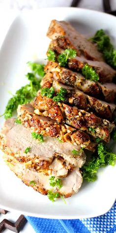 some meat is on a white plate and garnished with parsley, nuts