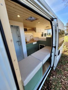 the interior of a camper van with its door open to reveal a kitchen and living area