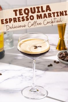 a glass filled with liquid sitting on top of a table next to a bottle of coffee