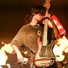 a man holding a bass in his right hand while standing next to another person on stage