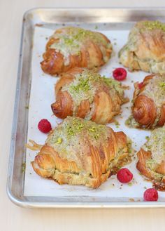 there are many croissants that have been baked on a baking sheet with raspberries