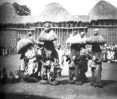 an old black and white photo of people dressed in native garb with straw umbrellas on their heads