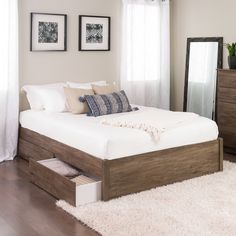 a bed sitting on top of a wooden floor next to a dresser under a window