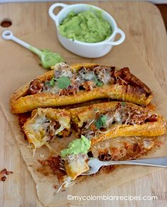 an enchilada with meat and guacamole is on a cutting board