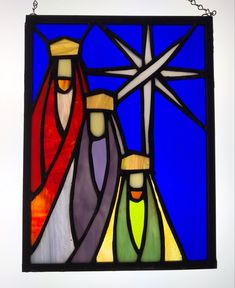 a stained glass window with three figures in the center and a star above it, on a white wall