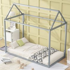 a metal bed frame with a white mattress and pillows on the floor in front of a yellow wall