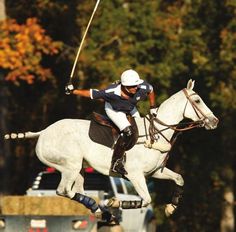 a man riding on the back of a white horse while holding a golf mallet