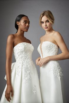 two women in white dresses standing next to each other