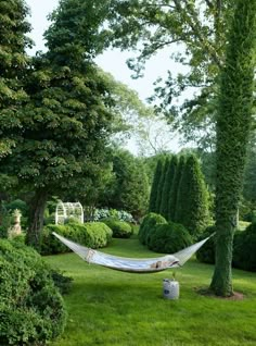 a hammock hanging between two trees in a garden