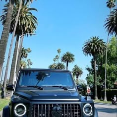 a black jeep parked on the side of a road with palm trees in the background