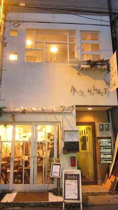 the outside of a restaurant with signs on the front and side of it at night