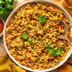 a large bowl filled with pasta and meat on top of a table next to other dishes