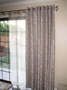 a living room with a sliding glass door that has curtains hanging on the side of it