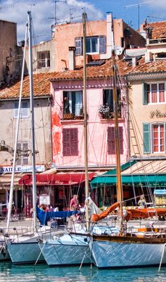 several sailboats are docked in the water near some buildings with red roofs and windows