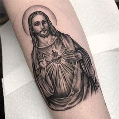 a black and white photo of a jesus tattoo on the arm