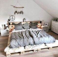 a bed made out of pallets in a room with white walls and wooden floors