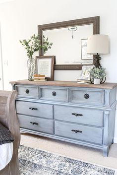 a blue dresser sitting next to a bed with a mirror on it's side