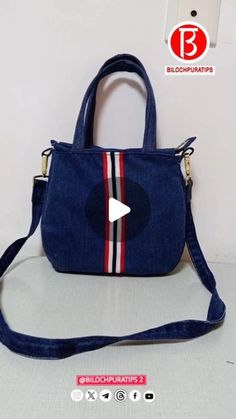 a small blue purse with a red, white and black stripe on the front pocket