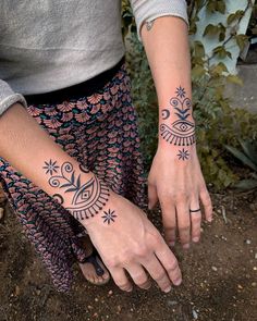 two people with matching tattoos on their arms and hands, both holding each other's hand