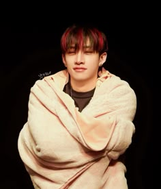 a young man with red hair wrapped up in a blanket and looking at the camera