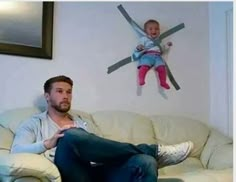 a man sitting on top of a white couch next to a baby in the air